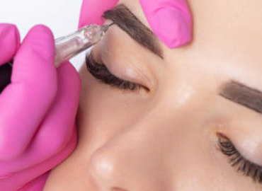 Sanitario aplicando la micropigmentación en las cejas de una mujer jóven