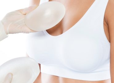 Mujer médico con prótesis mamarias se las muestra a una paciente jóven
