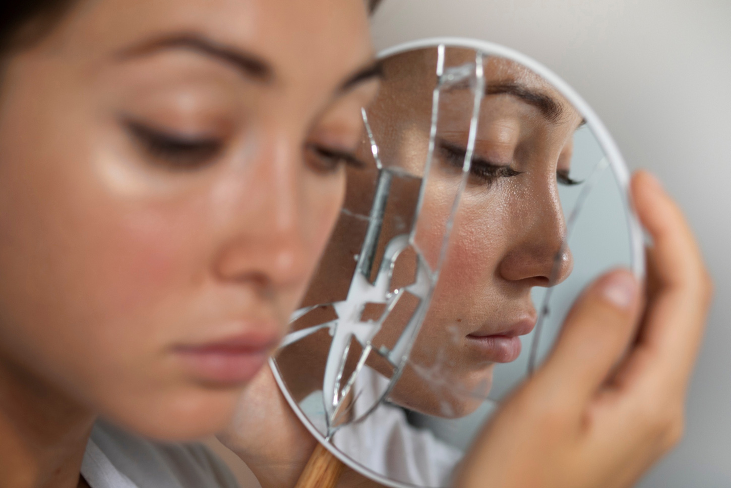 Mujer triste junto a un espejo roto